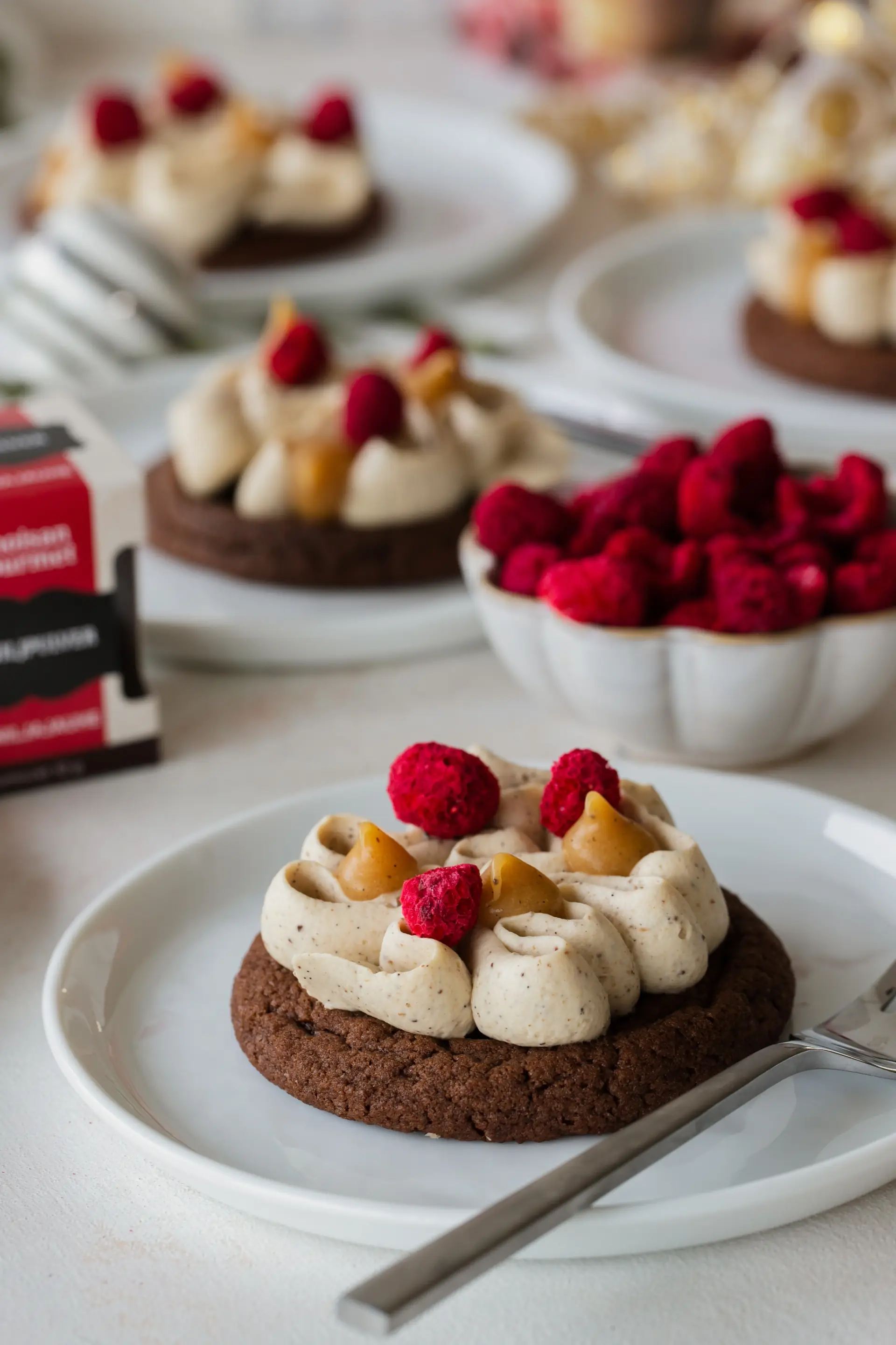 Chokladcookies med spritsad vispad pannacotta, vaniljsmörkola och frystorkade hallon